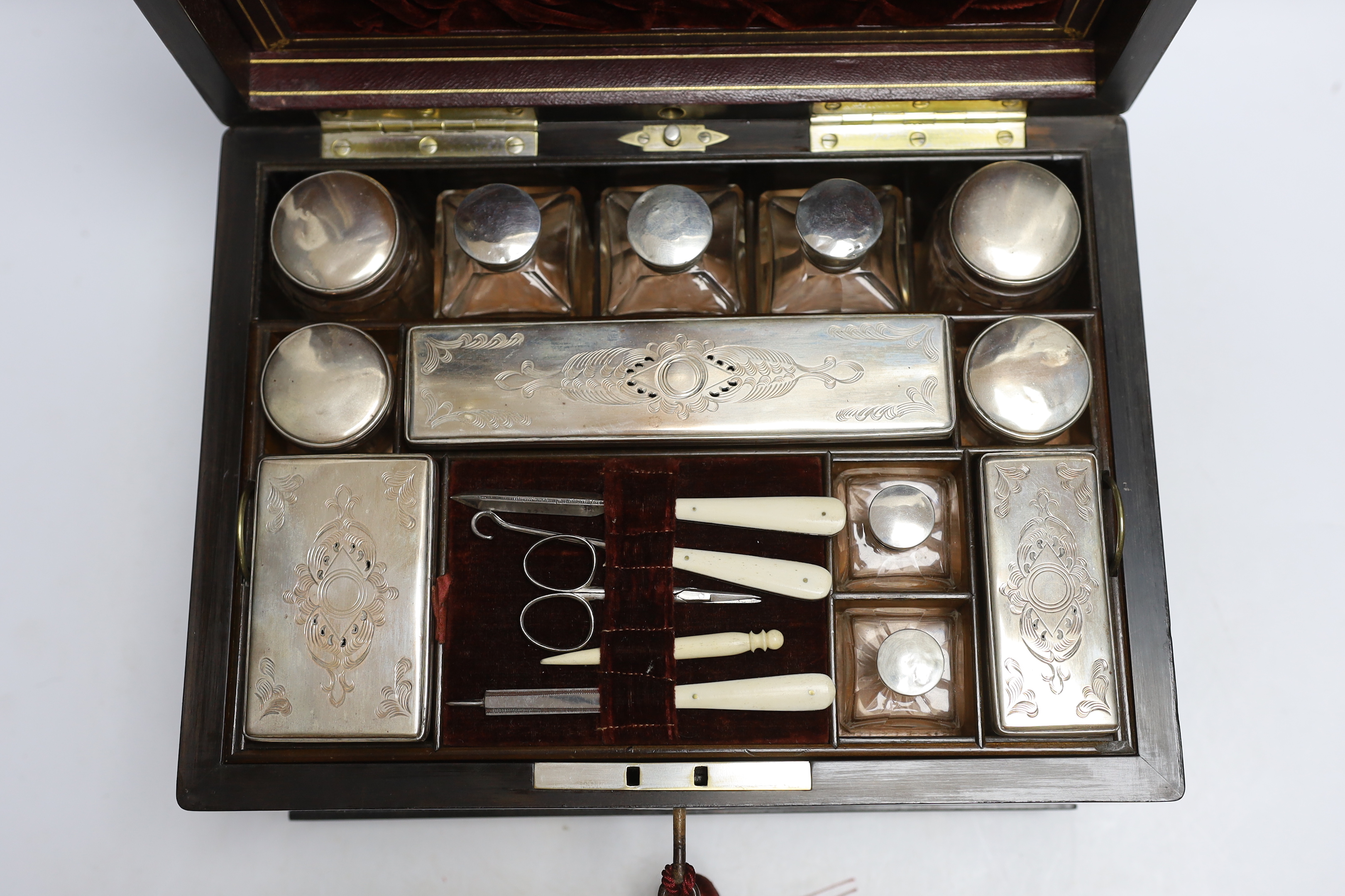 A Victorian coromandel wood toilet box with plated fittings and Mother of Pearl inlay to lid, fitted internal compartments containing glass bottles with plated lids and other accessories, and jewellery drawer underneath